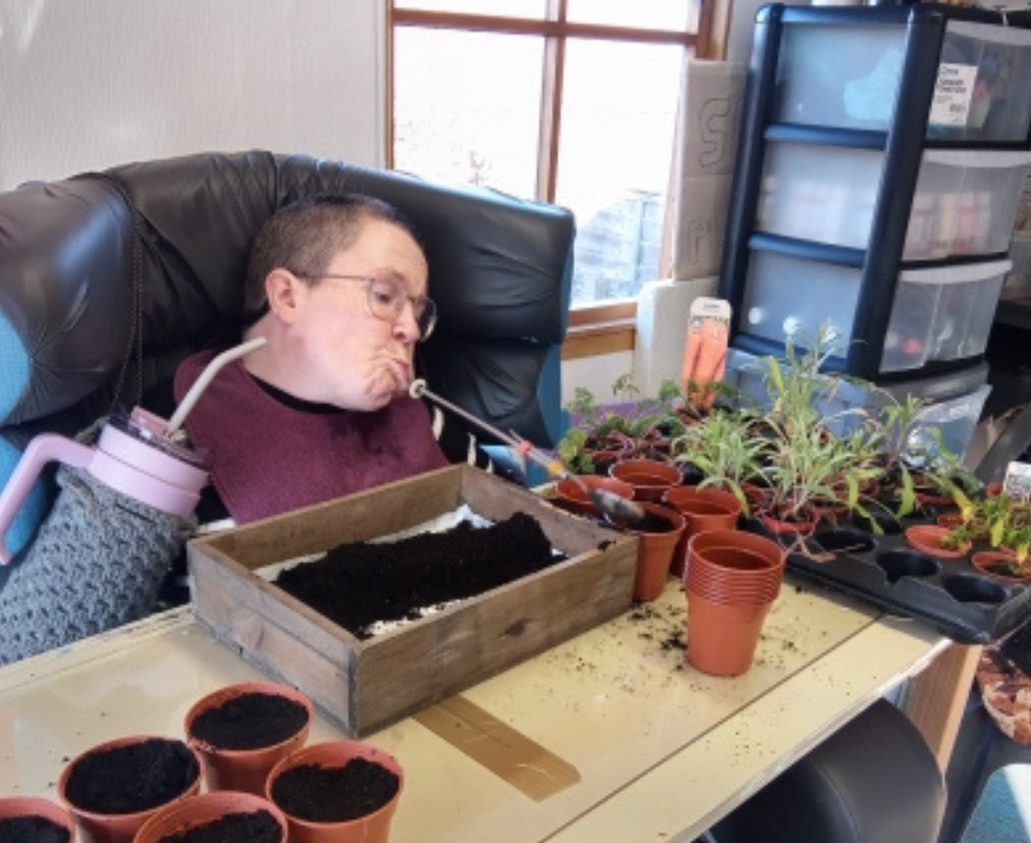 Services for Independent Living service user demonstrates using a mouth tool to carry out gardening tasks