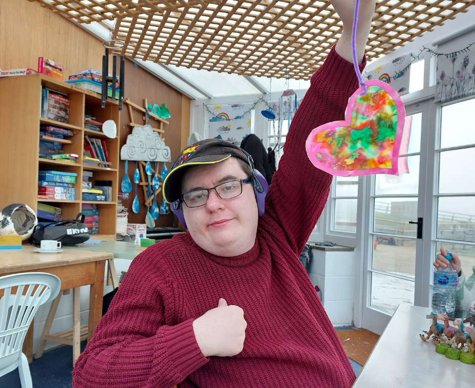 Service user from Services for Independent Living proudly shows a hand crafted heart decoration