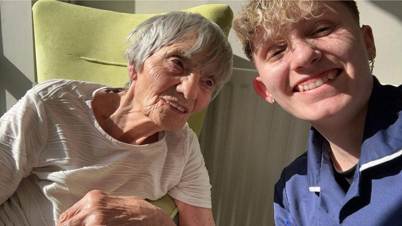 Young homecare support worker and older woman face the camera close up shot both smiling