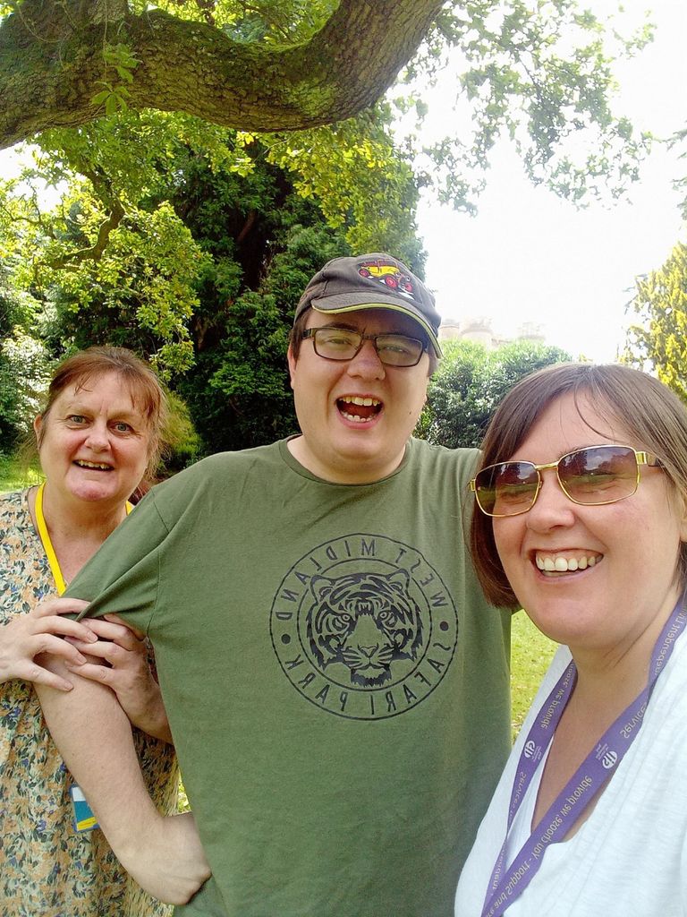 Group of three facing the camera smiling in an outdoor setting by an oak tree